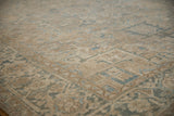 Distressed Heriz rug with beige and dusty blue geometric pattern and visible foundation.