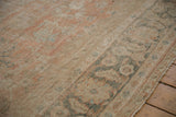 Angled view of the worn texture and meandering floral border of a distressed Mahal carpet.