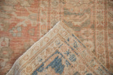 Folded corner of a distressed antique Mahal carpet revealing its hand-knotted weave and foundation.
