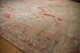 Angled view of a distressed Mahal carpet's worn texture over cinnabar red and powder blue florals.