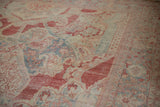 Soft, time-worn texture of a vintage Mahal carpet with distressed red and dusty blue floral patterns.