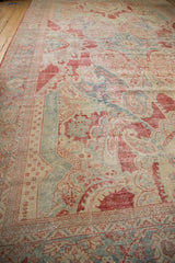 Side angle view of the distressed Mahal carpet's worn, low pile and sprawling floral motifs in red and blue.