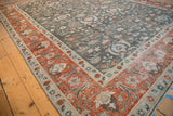 Distressed vintage Tabriz carpet corner with madder red border and charcoal floral patterns.