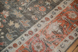 Distressed vintage Tabriz carpet showing floral patterns in madder root red, charcoal, and beige.