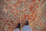 Distressed Heriz rug pile showing serrated leaf and palmette motifs in red, blue, and ivory.