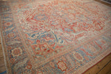 Angled view across a distressed Heriz rug, focusing on its wide Karaja-style border.