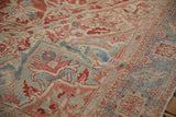 Serrated leaves and Karaja border details in cinnabar red and powder blue on a distressed Heriz rug.