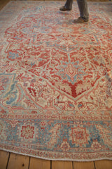 A person standing on the vintage distressed Heriz carpet, demonstrating its grand scale and worn texture.