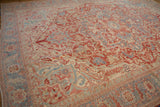 Angled view of a distressed Heriz carpet showing its faded gem tones and oversized medallion.