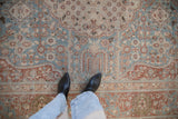 Distressed vintage Tabriz carpet showing a low-pile texture in dusty blue and plum hues.