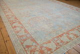 Angled view of the distressed Mahal carpet's soft blue floral field and terracotta border.