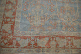 Corner detail of a distressed Mahal carpet showing its terracotta floral border and powder blue field.