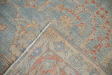 Folded corner of a distressed Mahal carpet showing the hand-knotted foundation and machine-bound edge.