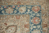 Corner borders of a distressed Persian rug with floral palmettes in sapphire blue and sand tones.