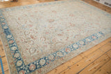 Full perspective of a vintage Persian carpet's sand-colored field and sapphire blue floral border.