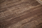 Close-up of vintage Tulu carpet's textured pile, coffee brown, dark chocolate, and oxidized silver striations.