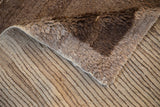 Close-up of vintage Tulu carpet's shaggy brown pile and striped hand-knotted foundation.