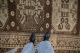 The scale and distressed texture of a vintage Kars carpet's geometric design in brown and pale seafoam.