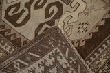 A vintage Kars rug corner folded to show the hand-knotted weave and brown selvage.