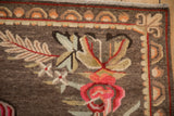 Detail of hand-knotted Khotan carpet: bright floral blossoms on coffee brown field.