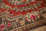 Vintage hand-knotted carpet detail: European-influenced floral blossoms, cherry red field, coffee brown accents.