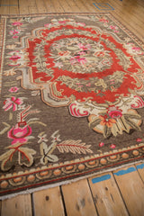 Vintage Khotan carpet with pink, tangerine, ivory floral patterns on coffee brown.