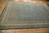 Distressed Mir Sarouk rug corner showing worn teal boteh field and intricate ivory border.