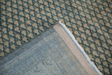 Visible foundation and fringe of a vintage distressed Mir Sarouk rug with worn teal pile.