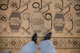 Repeating pattern of stylized vases holding germinating plants on a vintage Khotan carpet.
