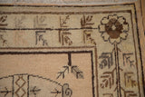Corner of a distressed Khotan carpet showing the floral blossom border and low, time-softened pile.