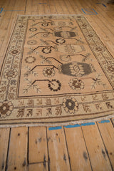 Angled perspective of a vintage distressed Khotan carpet showing its repeating vase and floral design.