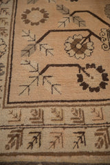 Close view of the hand-knotted floral border on a distressed vintage Khotan carpet.
