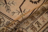 Textured low pile and brown stylized plant motifs on a folded vintage Khotan carpet.
