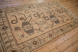 Distressed Khotan carpet from an angle, displaying its repeating vase pattern in brown and greige.