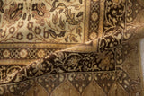 Folded corner of a vintage Kaisary rug showing the intricate floral borders in chocolate brown and sand tones.