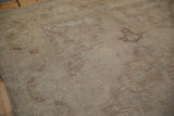 Low-pile texture of a distressed Oushak carpet showing worn beige and brown knot heads.