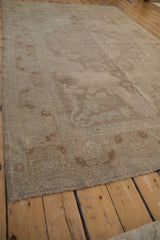 Angled view of the vintage Oushak's corner showing the distressed, low pile and serrated leaf border.
