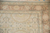 Corner of a distressed Kaisary carpet showing dusty rose floral vines and even, low pile.