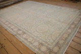 Angled view of a distressed Kaisary carpet with repeating roundel medallions and a dusty blush border.