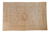 Distressed vintage Kaisary carpet with a starburst medallion and floral vines in ivory and pale coffee brown.