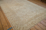 Angled perspective on a distressed Kaisary carpet, showcasing its sprawling vine pattern and starburst medallion in soft neutral tones.