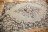 Geometric pale aubergine spandrel and border on the Oushak rug's time-softened pile.