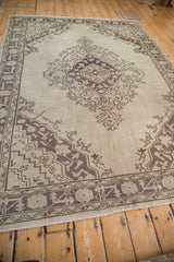 Faded geometric aubergine motifs on the distressed lower border of a vintage Oushak rug.