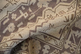Distressed Oushak carpet fold showing textured pile and faded aubergine geometric motifs.