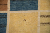 Textured pile of a vintage Gabbeh rug, showing blue, yellow, and brown panels with abrash.