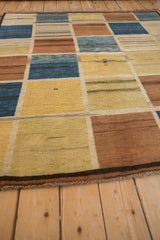 Vintage Gabbeh detail: repeating panels in dusty blue, saffron, copper, with human figure.