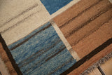 Textured pile with abrashes in dusty sapphire blue, pale coffee, and ivory panels.