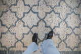 Top-down view of a distressed Moroccan carpet's soft texture and blue and ivory lattice design.