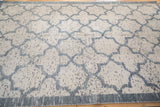 Angled view of the distressed carpet's textured pile and dusty blue lattice pattern.