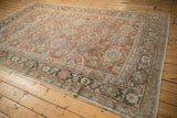 Distressed Mahal carpet corner: charcoal Herati palmette border, terracotta field, visible pile wear.